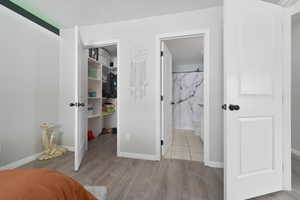 Bedroom featuring ensuite bathroom, a closet, and light tile floors