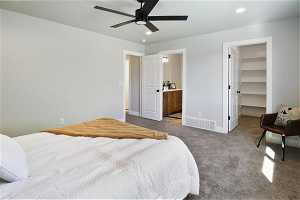 Carpeted bedroom with a spacious closet, ensuite bathroom, a closet, and ceiling fan