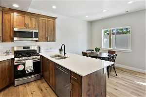 Kitchen with kitchen peninsula, sink, light hardwood / wood-style flooring, and stainless steel appliances