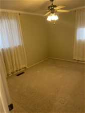 Carpeted empty room featuring ornamental molding and ceiling fan