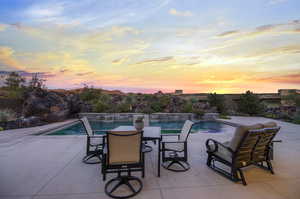 Pool at dusk featuring pool water feature and a patio