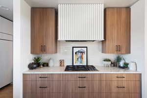 Kitchen featuring gas stovetop, backsplash, radiator, and hardwood / wood-style flooring