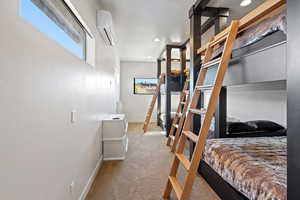 Carpeted bedroom featuring an AC wall unit