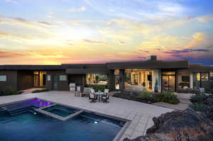 Pool at dusk with a patio and an in ground hot tub