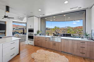 Kitchen featuring sink, light hardwood / wood-style flooring, double oven, ceiling fan, and white cabinets