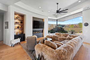 Living room featuring built in shelves, ceiling fan, and light hardwood / wood-style floors