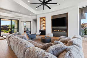 Living room featuring built in features, light wood-type flooring, ceiling fan, and a barn door