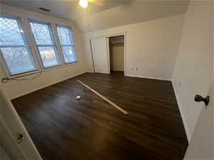 Unfurnished bedroom featuring dark hardwood / wood-style floors, ceiling fan, and a closet