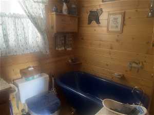 Bathroom featuring toilet, wooden walls, and a