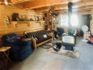 Living room with a wood stove, beamed ceiling, and light carpet