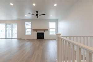 Unfurnished living room with a brick fireplace, ceiling fan, and light hardwood / wood-style floors