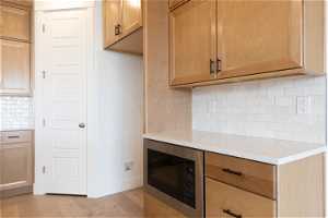 Kitchen featuring backsplash, light hardwood / wood-style floors, and black microwave