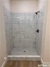 Bathroom with a tile shower and hardwood / wood-style flooring