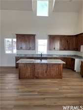 Kitchen with a kitchen island with sink, hardwood / wood-style floors, and a high ceiling