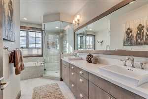 Master bathroom with double sink, tile flooring, large vanity, and shower with separate bathtub