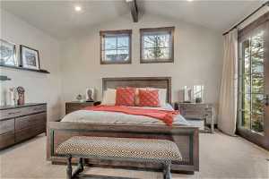 Master bedroom featuring vaulted ceiling with beams and light colored carpet