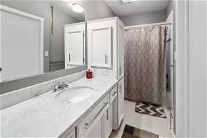Master Bathroom with oversized vanity, a textured ceiling, tile floors, and shower / tub combo with curtain