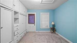 Unfurnished bedroom featuring a closet, light colored carpet, and a textured ceiling with built-in cabinets,