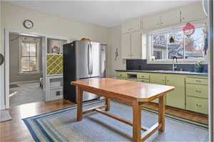 Kitchen featuring sink, carpet floors, stainless steel refrigerator, green cabinetry, and white cabinetry