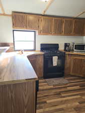 Kitchen featuring dark hardwood / wood-style flooring, black range with gas cooktop, and sink