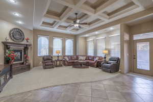 Living room with light carpet, ceiling fan, coffered ceiling, and beamed ceiling