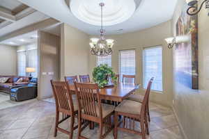 Dining space with light tile floors, an inviting chandelier, and a raised ceiling