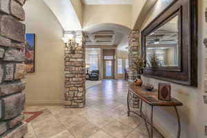 Tiled foyer entrance featuring coffered ceiling, ceiling fan, and beamed ceiling