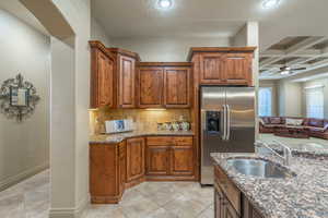 Kitchen featuring sink, high quality fridge, coffered ceiling, beam ceiling, and ceiling fan