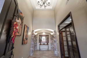 Tiled entrance foyer featuring a chandelier, a raised ceiling, and a towering ceiling