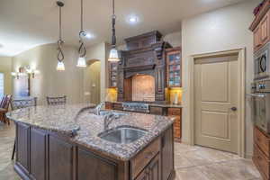 Kitchen with light tile flooring, sink, an island with sink, and stainless steel appliances