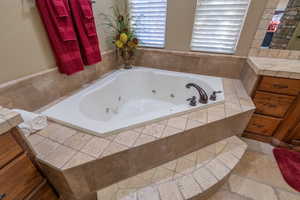 Bathroom with tile flooring and a relaxing tiled jetted tub