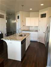 Kitchen with sink, a kitchen breakfast bar, hanging light fixtures, stainless steel appliances, and white cabinetry