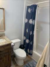 Full basement bathroom with shower / bath combination with curtain, vanity, toilet, and wood-type flooring