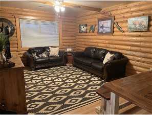 Cabin Living room featuring light hardwood / wood-style flooring, ceiling fan, and rustic walls