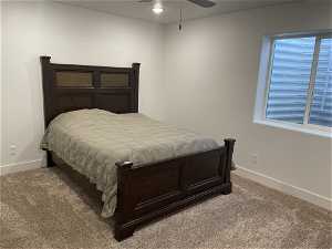 Carpeted bedroom with ceiling fan with walk-in closet