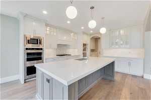 Kitchen featuring a large island with sink, appliances with stainless steel finishes, tasteful backsplash, and sink