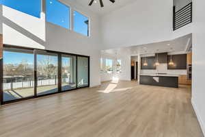 Living room towering ceiling, ceiling fan, and light hardwood / wood-style floors