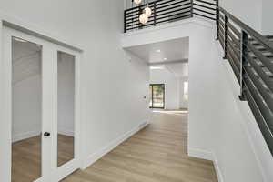 Hall with a towering ceiling, light hardwood / wood-style flooring, and french doors