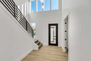 Foyer entrance with light hardwood / wood-style flooring and a high ceiling