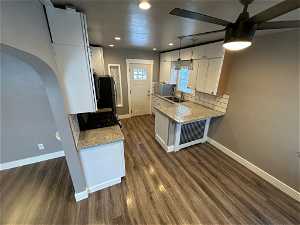 Kitchen featuring dark wood-type flooring, pendant lighting, tasteful backsplash, ceiling fan, and white cabinetry