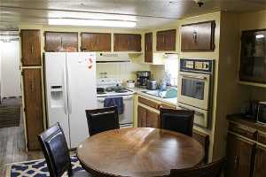 Kitchen featuring dark wood-type flooring, white appliances, a textured ceiling, and sink