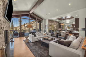 Living room featuring wood-type flooring, vaulted ceiling with beams, and a fireplace