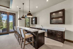 Bar with sink, hanging light fixtures, stainless steel dishwasher, dark brown cabinets, and french doors