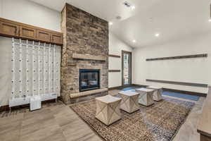 Living room featuring a stone fireplace and high vaulted ceiling