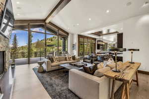 Living room with a fireplace, lofted ceiling with beams, and wood-type flooring