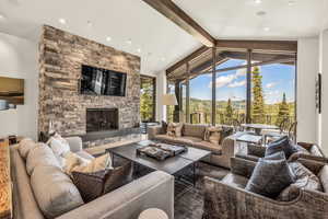 Living room with a stone fireplace and lofted ceiling with beams