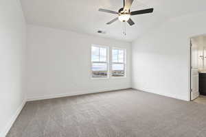 Carpeted empty room featuring ceiling fan and vaulted ceiling