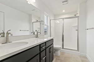 Bathroom with tile patterned flooring, a shower with shower door, vanity, and toilet