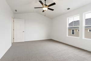 Carpeted empty room with ceiling fan and lofted ceiling