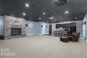 Theater room with a drop ceiling, a stone fireplace, and carpet floors